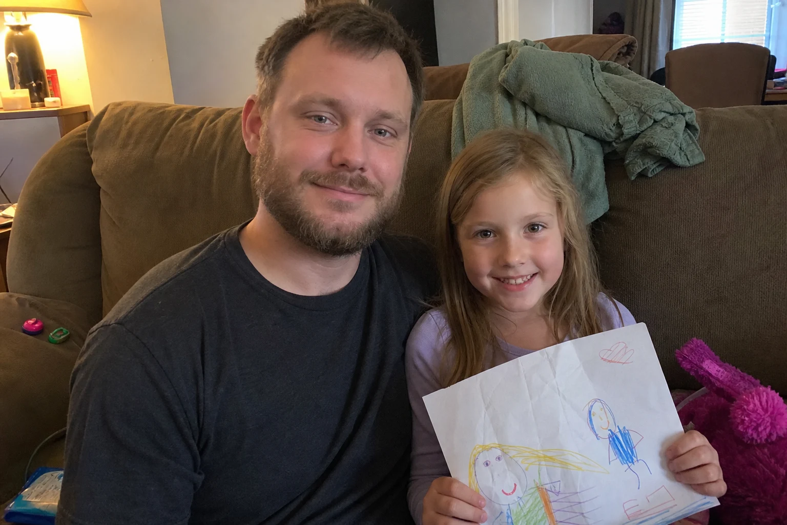 Father and daughter sitting together with her drawing